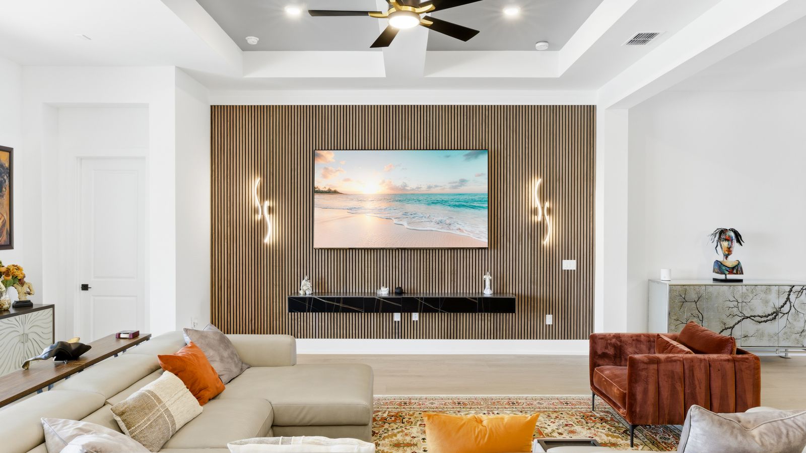 Living room with a wall-mounted TV set into a floor-to-ceiling natural wood slat wall, a floating console and LED wall sconces